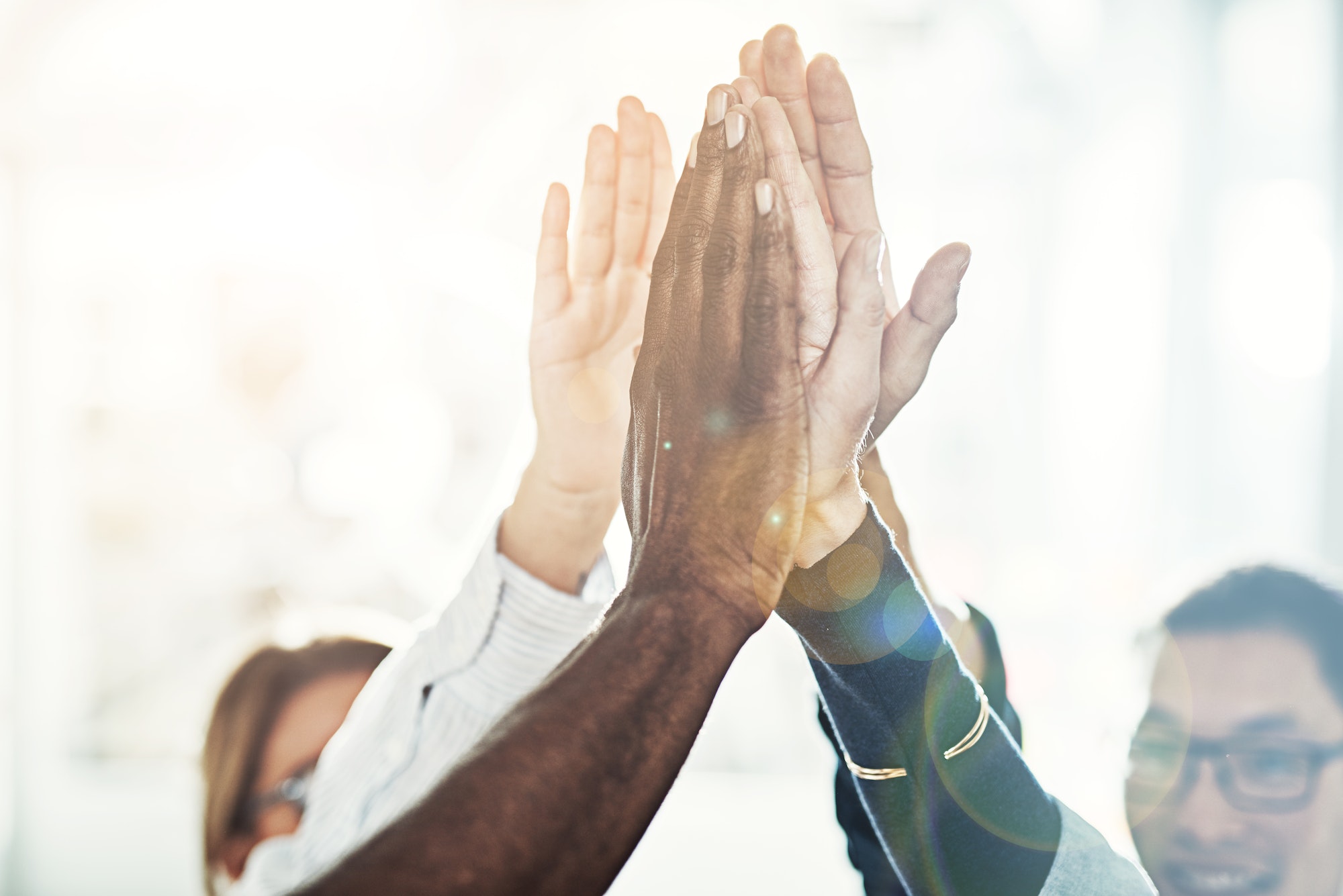 Diverse businesspeople high fiving together in an office